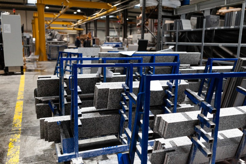 Produktionshalle mit Metallgestellen und zugeschnittenen Steinplatten.