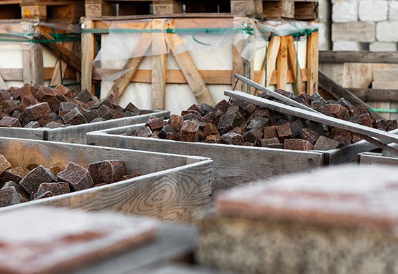 Steinverlegung mit Natursteinen und Werkzeugen auf einer Baustelle.
