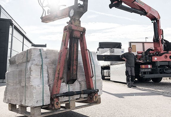 Baumaschine hebt schwere Steinblöcke mit Klammer.