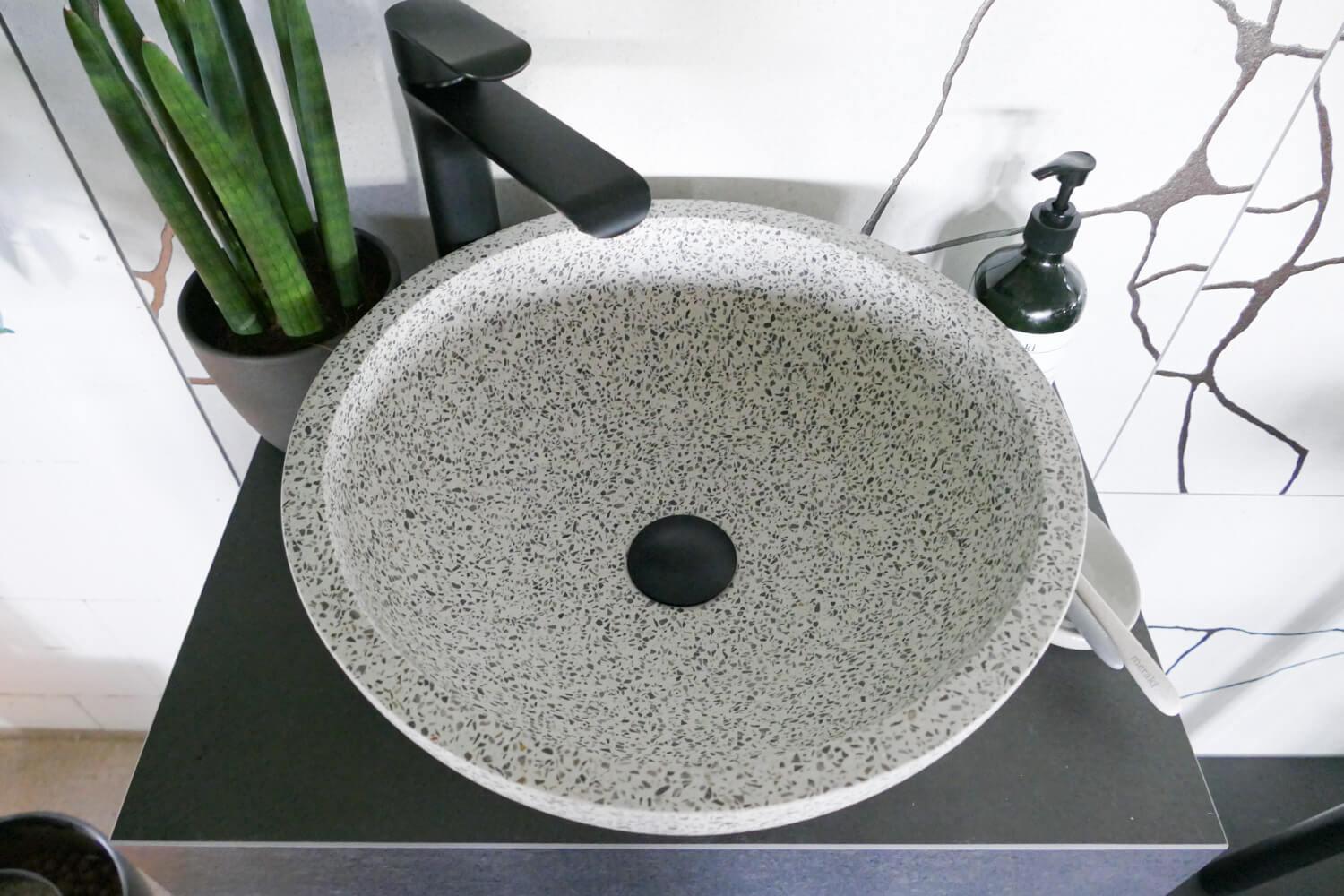 Terrazzo Waschbecken in grau mit schwarzem Ablaufventil und Armatur