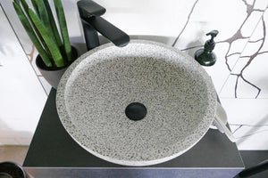 Terrazzo Waschbecken in grau mit schwarzem Ablaufventil und Armatur